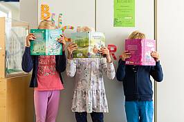 Drei Kinder verstecke sich hinter ihren Büchern