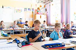 Schülerinnen und Schüler spielen gemeinsam Blockflöte im Klassenraum