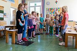 Mehrere Schülerinnen und Schüler stehen zusammen und singen gemeinsam