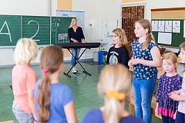 Mehrere Schüler und Schülerinnen singen gemeinsam. Die Lehrerin begleitet dazu am Keyboard.