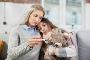 Mutter und Tochter schauen bedrückt auf ein Fieberthermometer